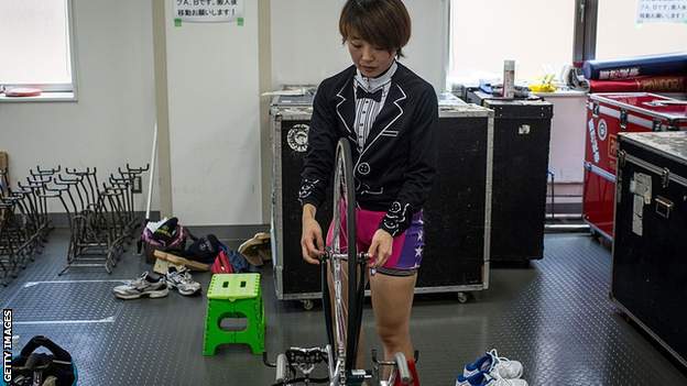 A female rider prepares her bike for inspection