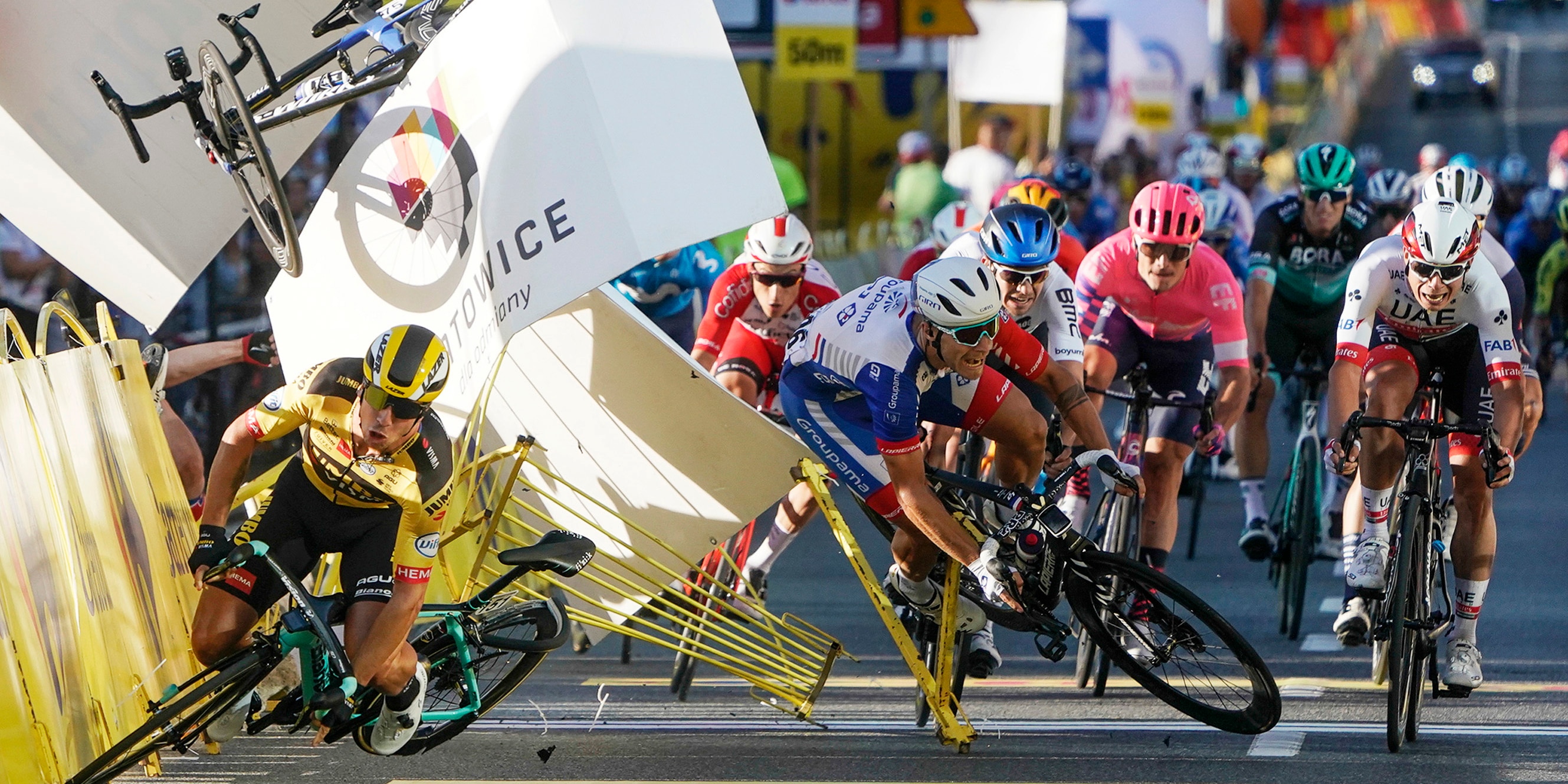 Dutch cyclist Dylan Groenewegen crashes to the ground as a bicycle is flying overhead in a major collision on the final stretch of the opening stage of the Tour de Pologne race in Katowice, Poland, Wednesday, Aug. 5, 2020. The crash began with Groenewegen colliding with another Dutchman sprinting for the win, Fabio Jakobsen, who was hospitalized in serious condition and put into an induced coma. Jakobsen was declared the winner of the opening stage and Groenewegen was disqualified. (AP Photo/Tomasz Markowski)