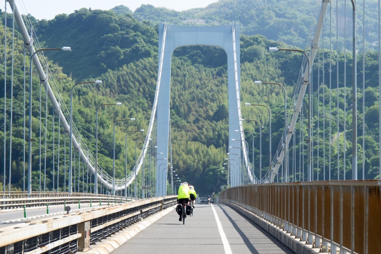 gbx92y two cyclists crossing the hakata oshima bridge connecting the islands of oshima and hakata in the seto inland sea