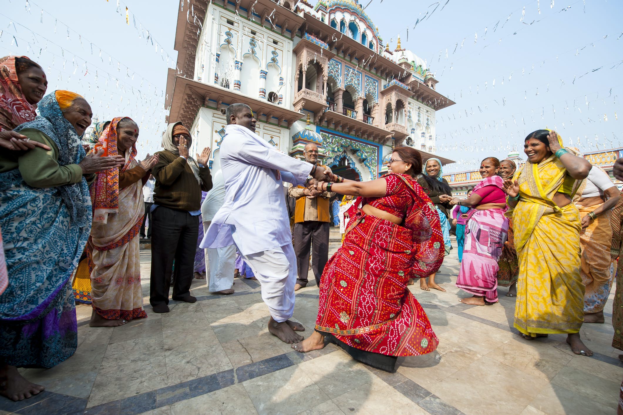 Hindu pilgrims laugh and smile as a couple dances in a circle of onlookers