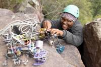 Partner in adventure grant recipient Zorbari Nwidor practicing anchor building by fitting different sized cams into a rock.