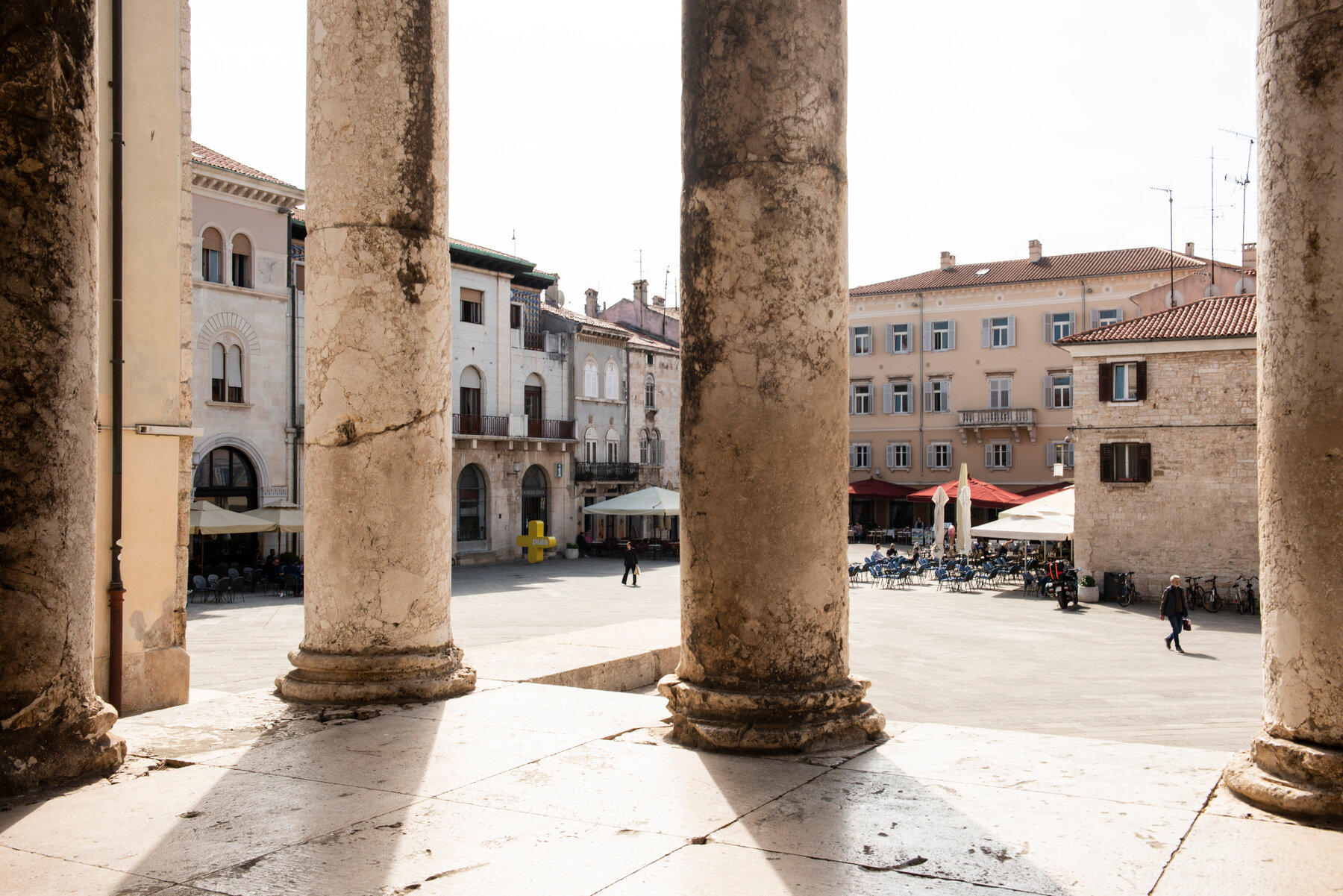 View of restaurants in a square through large pillars.